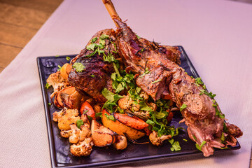 Juicy roasted leg of lamb with fruits and vegetables on tablecloth background