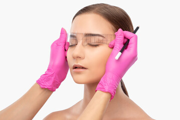 Make-up artist makes markings with white pencil for eyebrow and paints eyebrows. Professional...