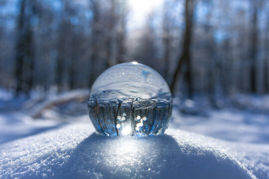 Glaskugel liegt auf dem Waldboden im Schnee