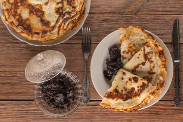 pancakes with plum jam and tea on wooden background