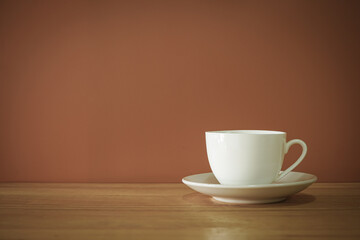 White coffee cup on wooden desk with brown background