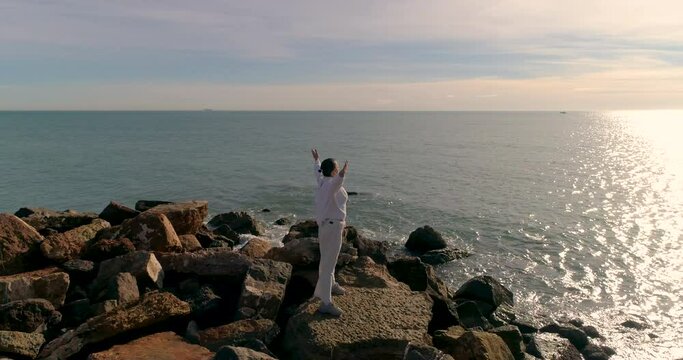 dron orbita a mujer de blanco con brazos levantados cara al sol