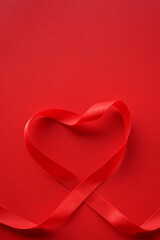 Red ribbon with heart shape on red background. Valentines day Or Love background concept. 