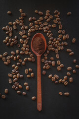 Ground coffee in wooden spoon with coffee beans on black background 