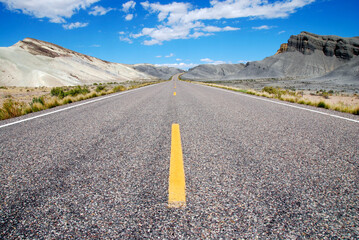motorcycle riding the badlands of artist's Drive in Death Valley National Park with empty highway and scenic landscape