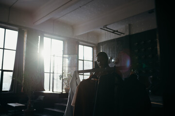 Photo of a man in an apartment standing against the background of a window from which the sun glare is visible