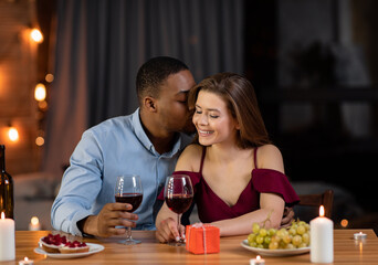 Multiracial couple dating and drinking wine during romantic dinner in restaurant