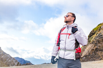 Young bearded man wearing white puff jacket standing near a mountain