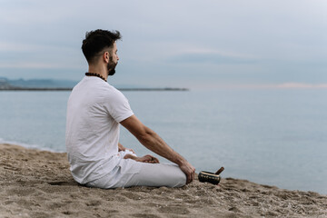 Man doing meditation exercises on the beach at dawn