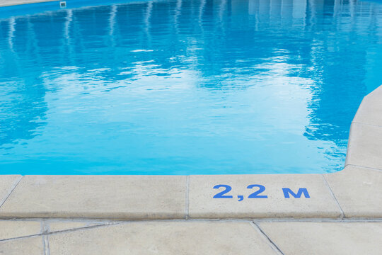 close up image of signs of depth in meters in swimming pool, deep pool with blue water, no people around,  safety on water