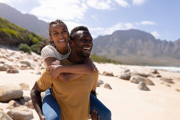 African american couple piggybacking on a beach by the sea