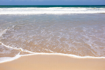 Beautiful beach by the sea and with big waves and golden sand on a sunny day