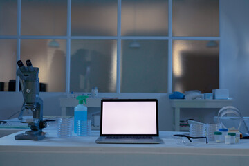 Laptop computer with illuminated screen at workstation in medical laboratory