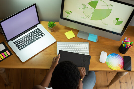 Overhead view of african american woman using graphic tablet while working from home - Powered by Adobe