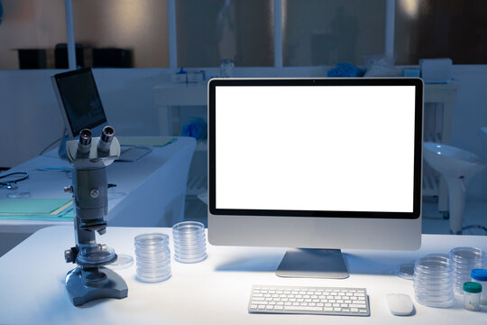 Desktop Computer With Illuminated Screen At Workstation In Medical Laboratory