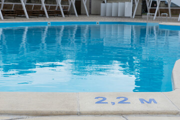 signs of depth in meters in swimming pool, deep pool with blue water, no people around,  safety on water