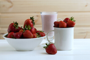 red juicy ripe strawberries in a white dish on a white wooden background, berries, vitamins, space for text