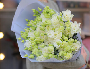 Nice young woman holding beautiful mono bouquet of fresh white eustoma flowers, cropped photo,...