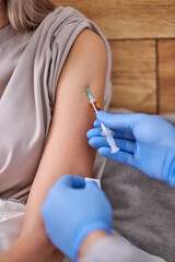 home doctor service. cropped doctor with syringe doing injection vaccine to young woman,...