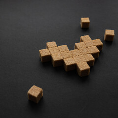Heart symbol for Valentine's Day holiday. Refined cane sugar on a black background. Confession of feelings and an addiction to sweets