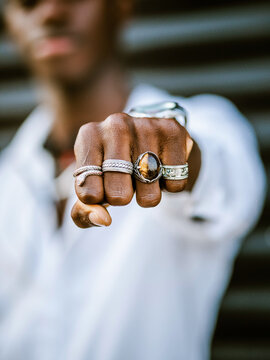 Blurred anonymous African American stylish male showing fist with various trendy silver rings