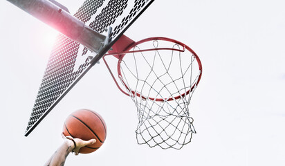 From below of crop hand of anonymous male player shooting ball to hoop while playing basketball on sports ground on street