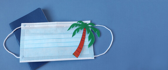 Banner : medical mask with a painted palm tree on the passport on a blue background, space for text