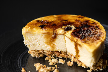 Closeup of delicious creme brulee cheesecake served on plate in bakery on black background
