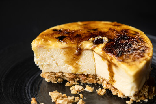 Closeup of delicious creme brulee cheesecake served on plate in bakery on black background