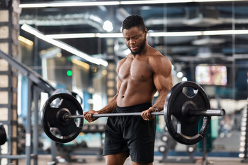 Fototapeta na wymiar Muscular shirtless bodybuilder exercising with barbell at gym