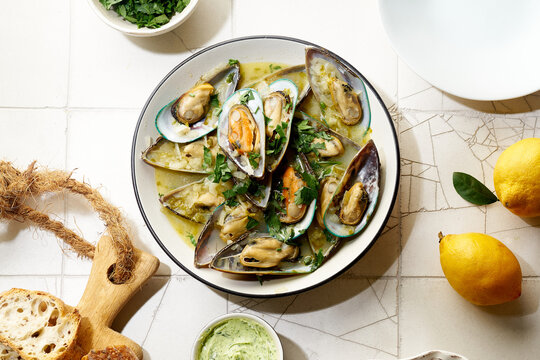 Cooked kiwi green mussels with wine, garlic and parsley served with baguette and butter with herbs