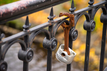 Fototapeta na wymiar Rusty car engine piston hanging on fence of bridge as wedding padlock.