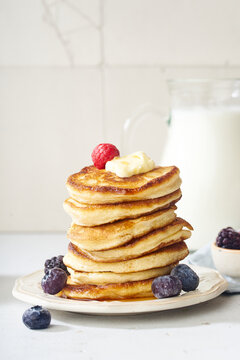 Fluffy breakfast pancakes with maple syrup and berries