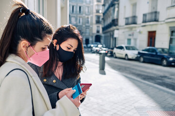 Two women shopping with their credit card and using the phone.