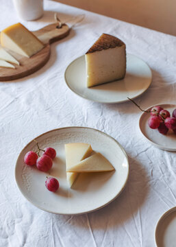 High angle of various palatable cheese arranged on table with Anona fruits and grapes near ceramic jug