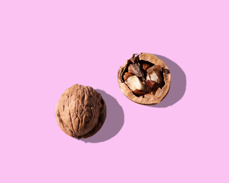 Ripe half peeled walnut at pink background in studio