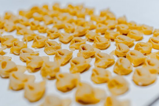 Rows of raw traditional Italian tortellini placed on baking pan in bright kitchen