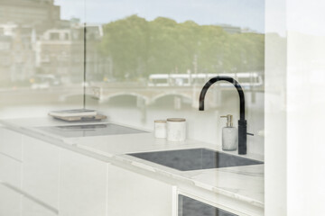 A minimalistic kitchen sink and faucet. Luxury kitchen interior. White sink in modern kitchen