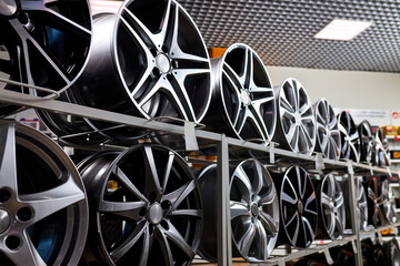 stand with alloy wheels in modern tire store, close up photo of auto wheels in auto service shop