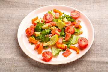Salmon salad with cherry tomatoes and green salad in a plate of gray tablecloth.