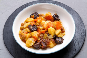 Jewish cuisine dish sweet zimmes with vegetarian dates carrots in a plate on a concrete background.