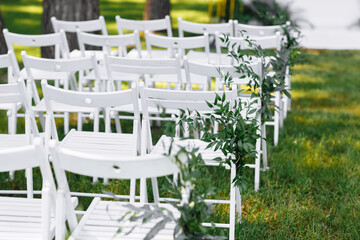decorated white chairs at a wedding ceremony