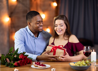 Valentine's Day Celebration. Happy Romantic Interracial Couple Dining In Restaurant, Exchanging Gifts
