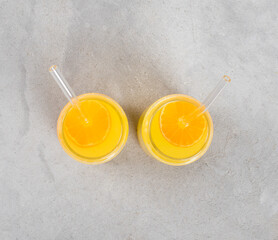 Refreshing mandarin drink in a glass jar with a straw on a light gray background top view