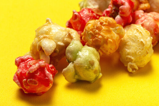 From above closeup of sweet colorful popcorn scattered on yellow background in studio