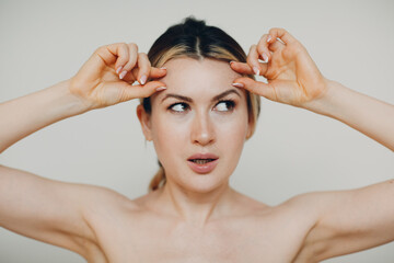 Fototapeta premium Young adult doing facial gymnastics self massage and rejuvenating exercises face building for skin and muscles lifting