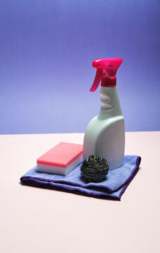 Top view of spray detergent arranged on pink and blue background with sponges and rag for cleaning concept
