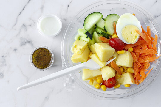 From above of various delicious vegetables and boiled egg placed in plastic container for takeaway food