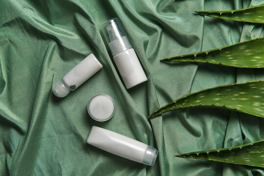 From above of arrangement of aloe vera leaves and various cosmetic products on green fabric