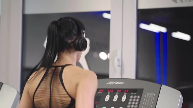 Fitness woman running on treadmill in gym. Athlete woman using run machine in fitness center.
